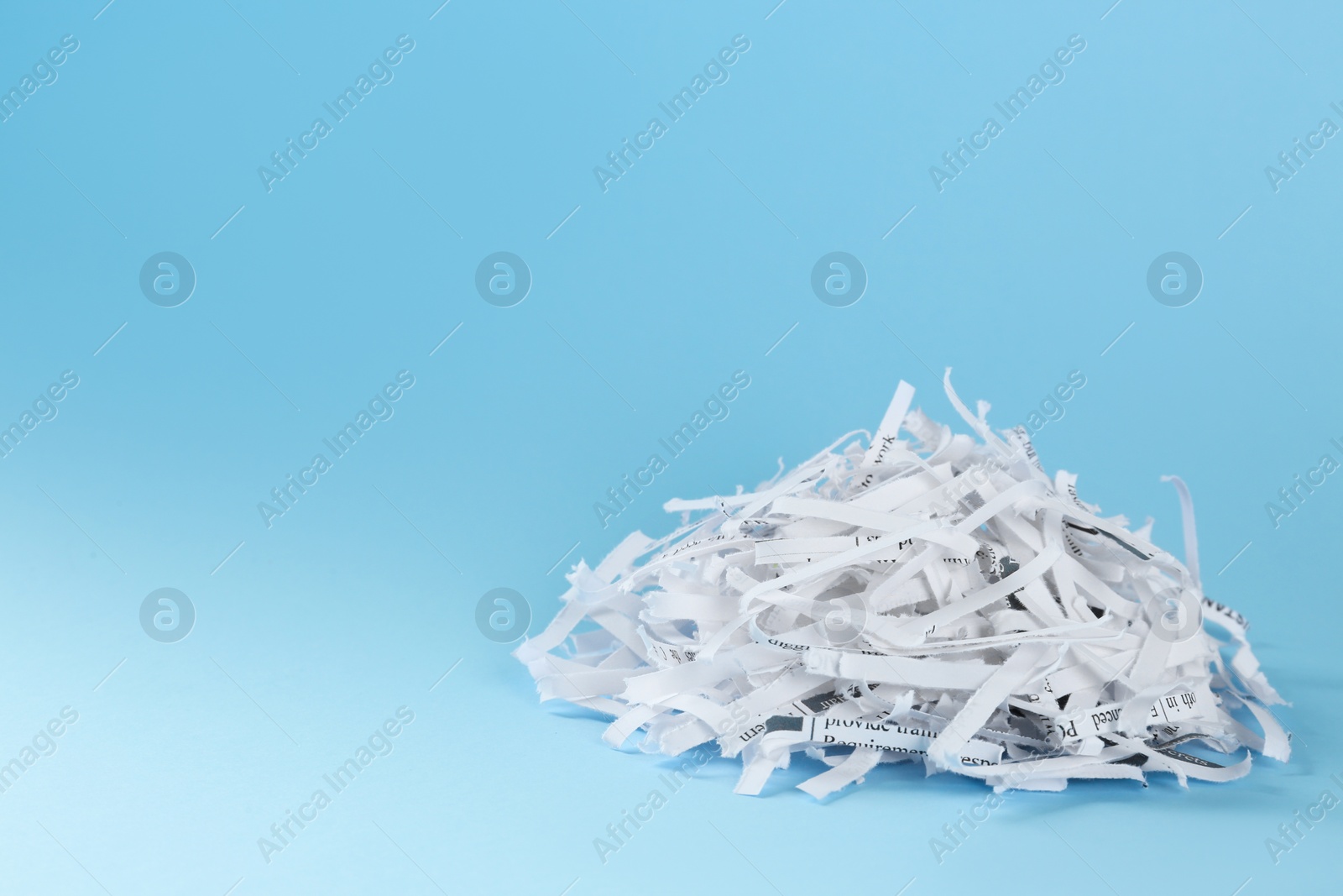 Photo of Heap of shredded paper strips on light blue background, space for text