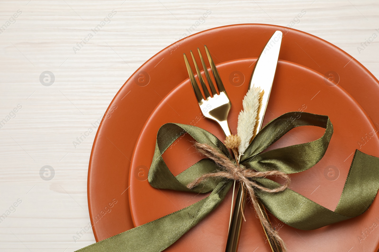 Photo of Beautiful autumn table setting with green bow on white wooden background, top view