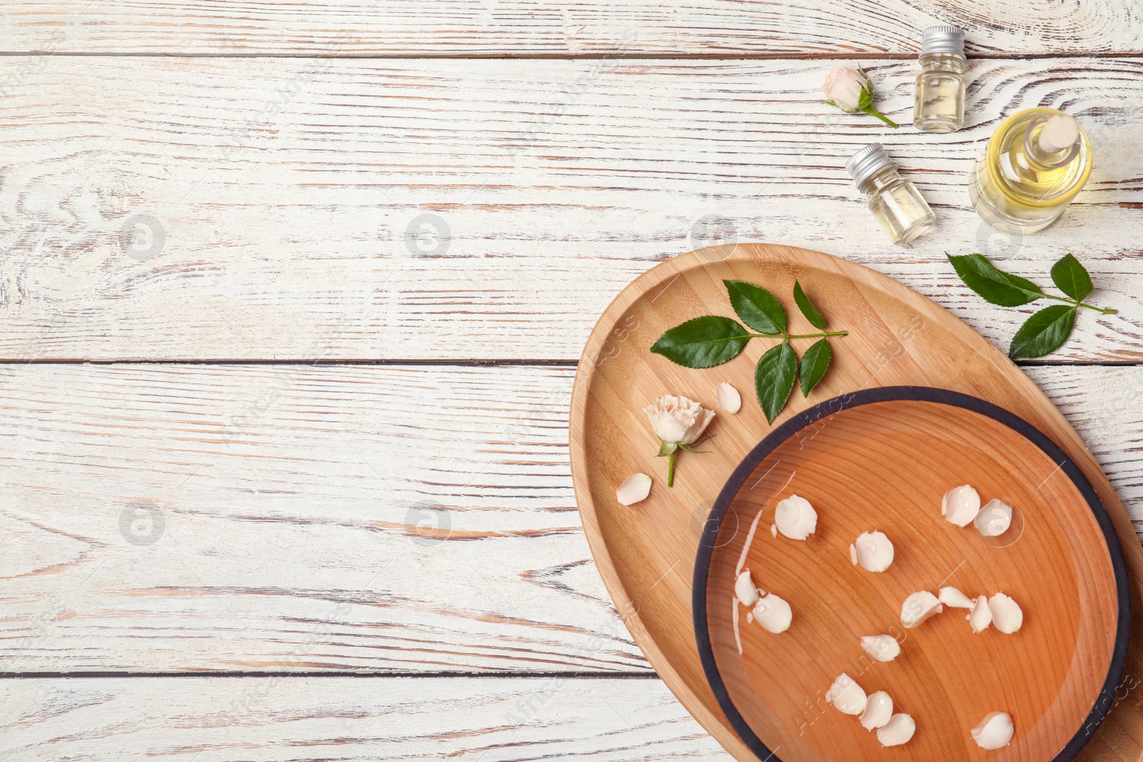 Photo of Essential oil, ingredients and space for text on wooden background, flat lay