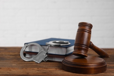 Gavel, handcuffs and books on wooden table. Criminal law