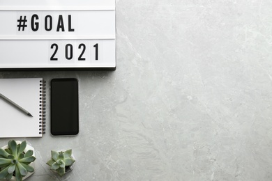 Light box with hashtag Goal 2021, new year targets. Objects and space for text on grey table, flat lay