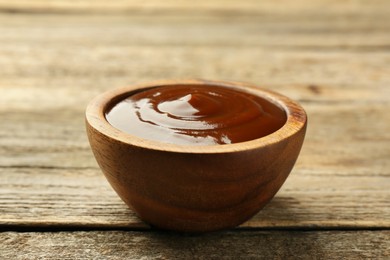 Photo of Tasty barbeque sauce in bowl on wooden table, closeup