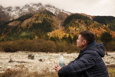 Photo of Boy holding thermo bottle with drink in beautiful mountains