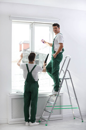 Professional workers tinting window with foil indoors