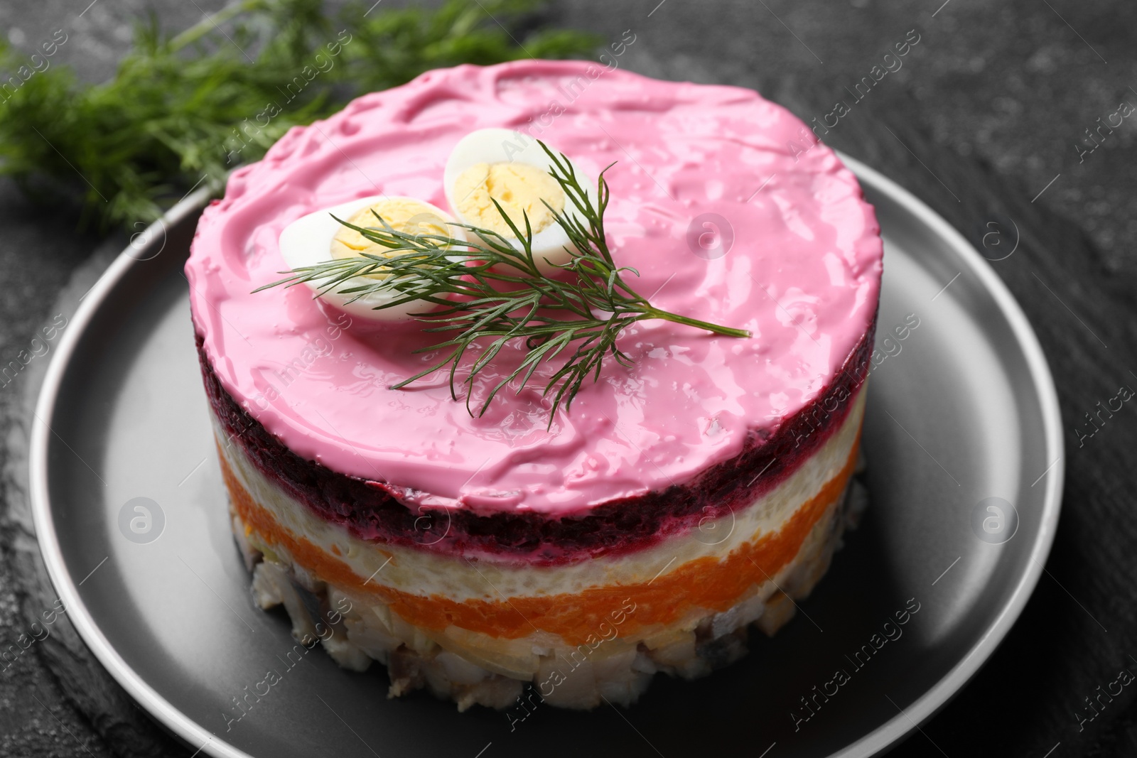 Photo of Herring under fur coat salad on grey table, closeup. Traditional Russian dish