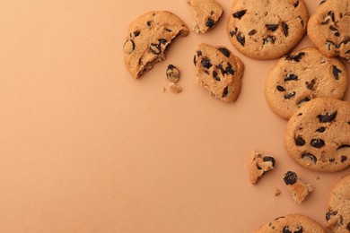 Photo of Many delicious chocolate chip cookies on beige background, flat lay. Space for text