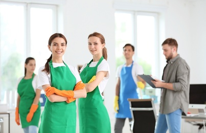 Photo of Team of professional janitors in uniform indoors