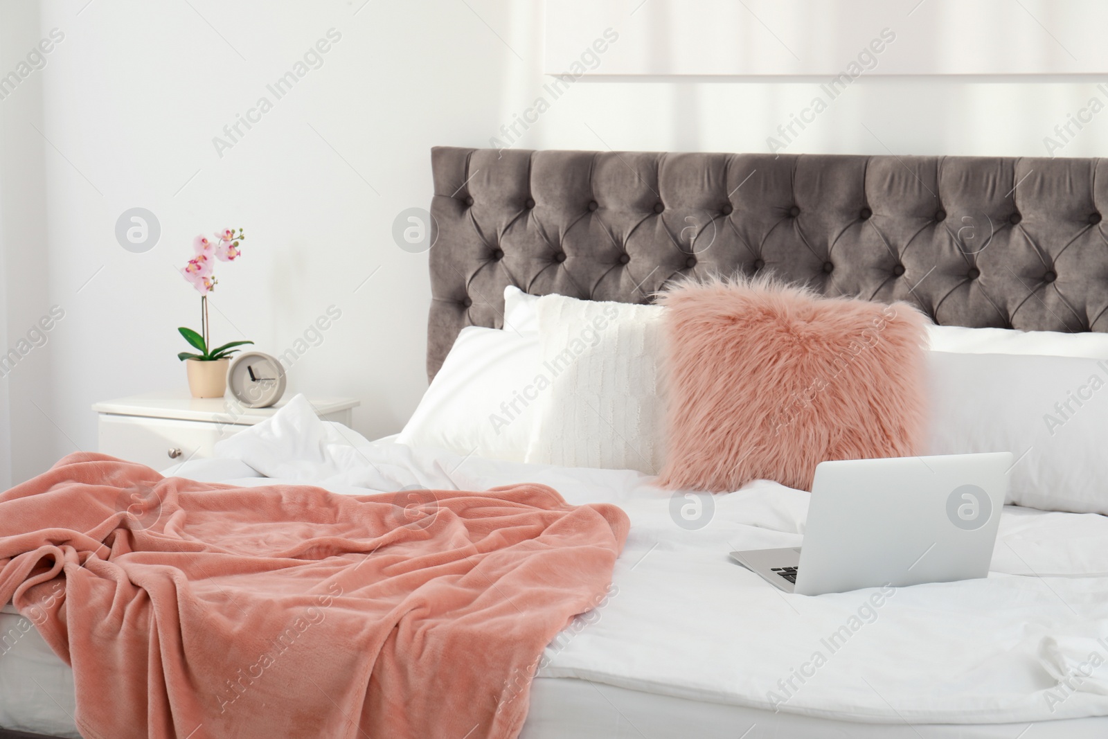 Photo of Laptop on bed in stylish room interior