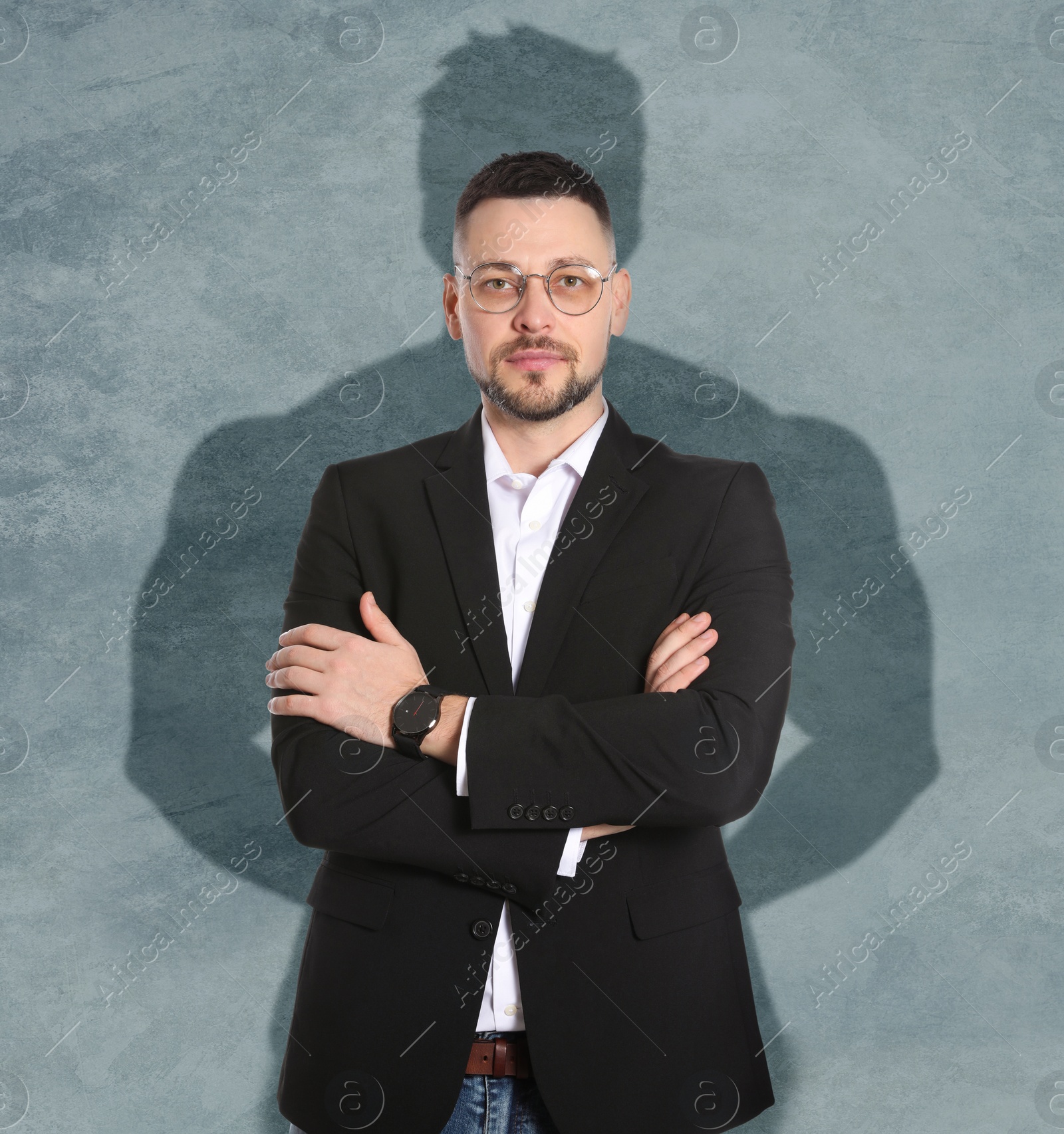 Image of Businessman and shadow of strong muscular man behind him on grey wall. Concept of inner strength