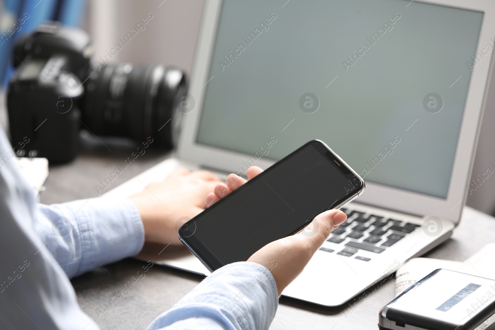Photo of Journalist with smartphone working at table in office, closeup