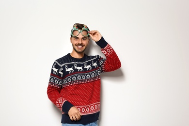 Photo of Young man in Christmas sweater with party glasses on white background