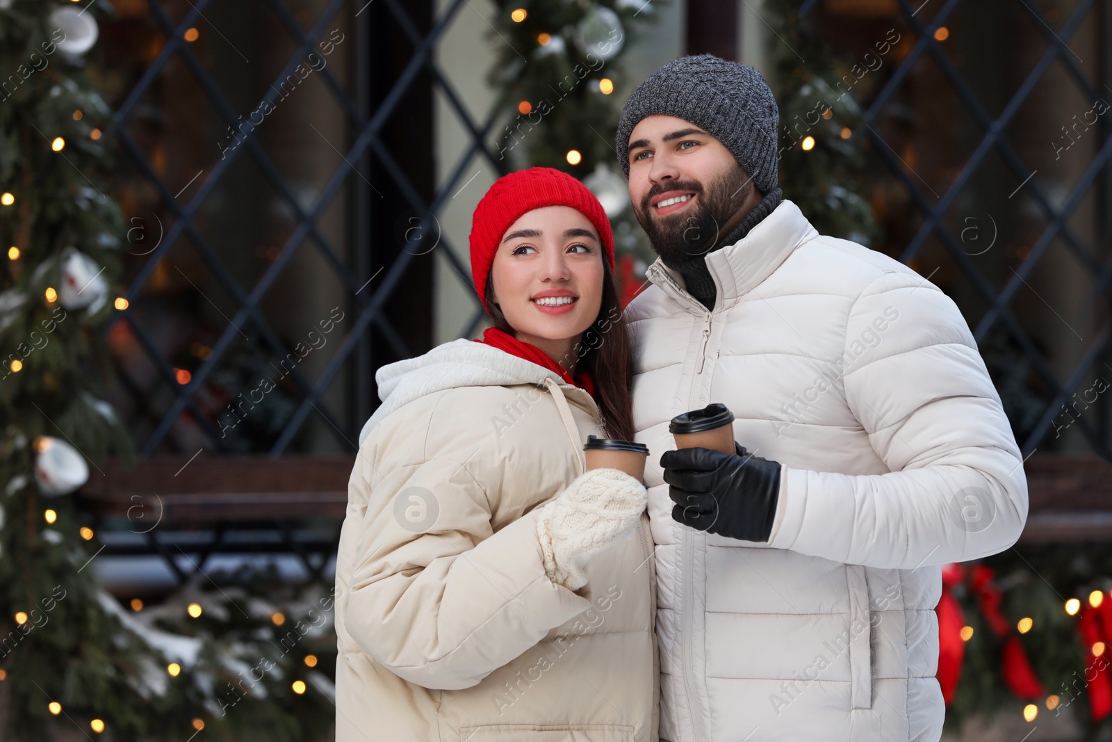 Photo of Lovely couple with hot drinks spending time together on city street