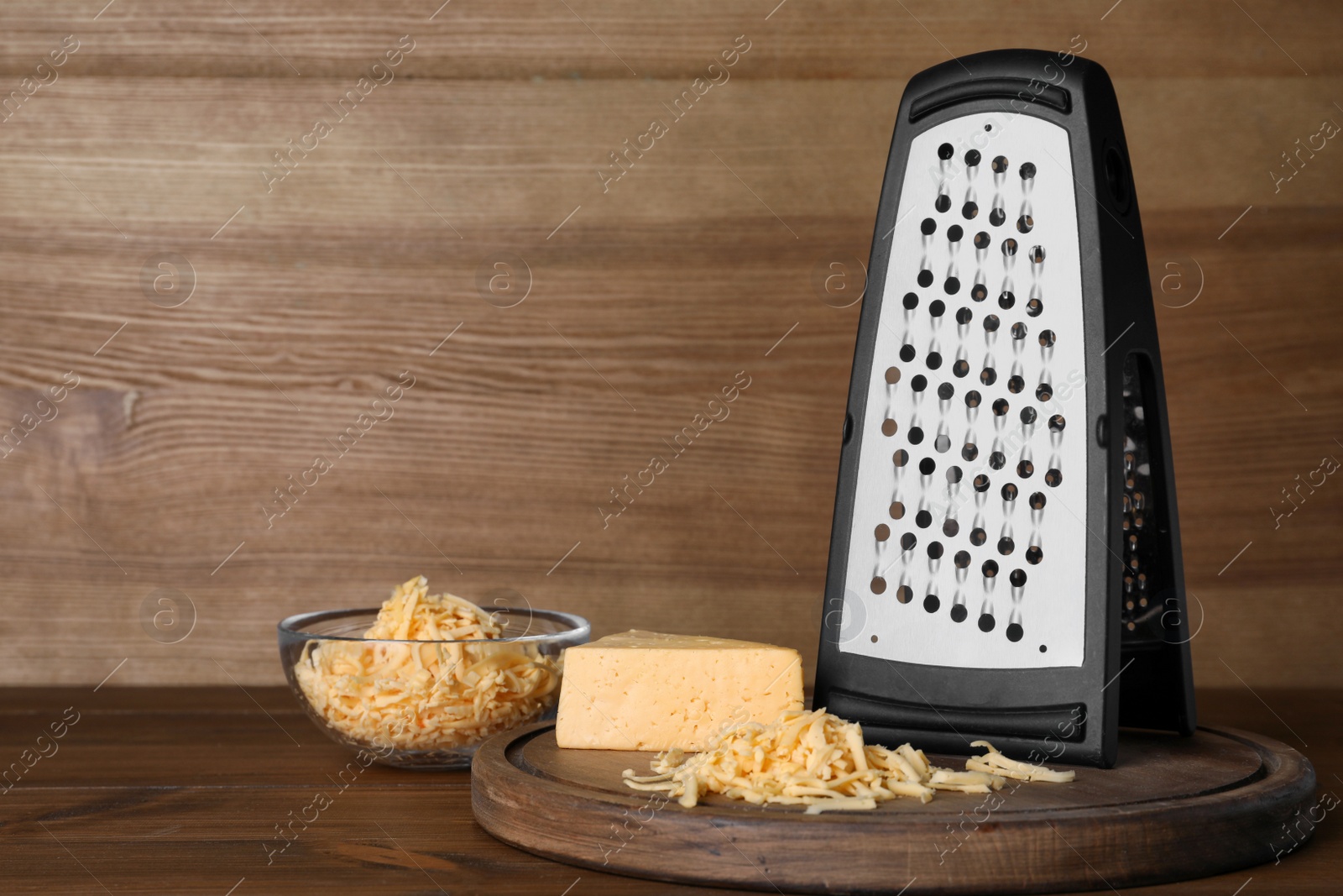 Photo of Grater and delicious cheese on wooden table. Space for text