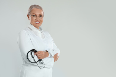 Photo of Portrait of mature doctor with stethoscope on light grey background. Space for text