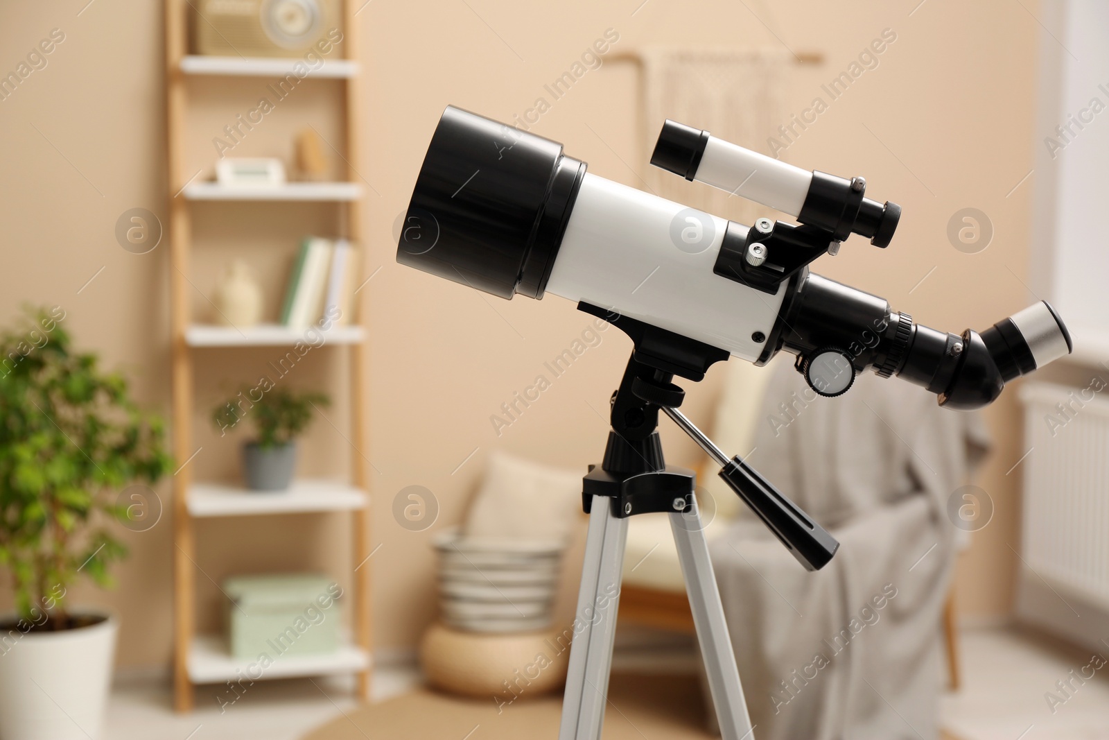 Photo of Tripod with modern telescope in stylish room, closeup