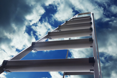 Metal stepladder against blue sky with clouds, low angle view