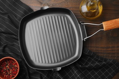 Photo of Grill frying pan, oil and spices on wooden table, flat lay. Cooking utensils