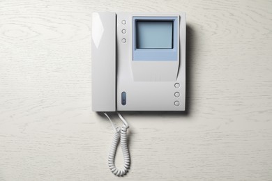 Modern intercom system with handset on white wooden background, top view