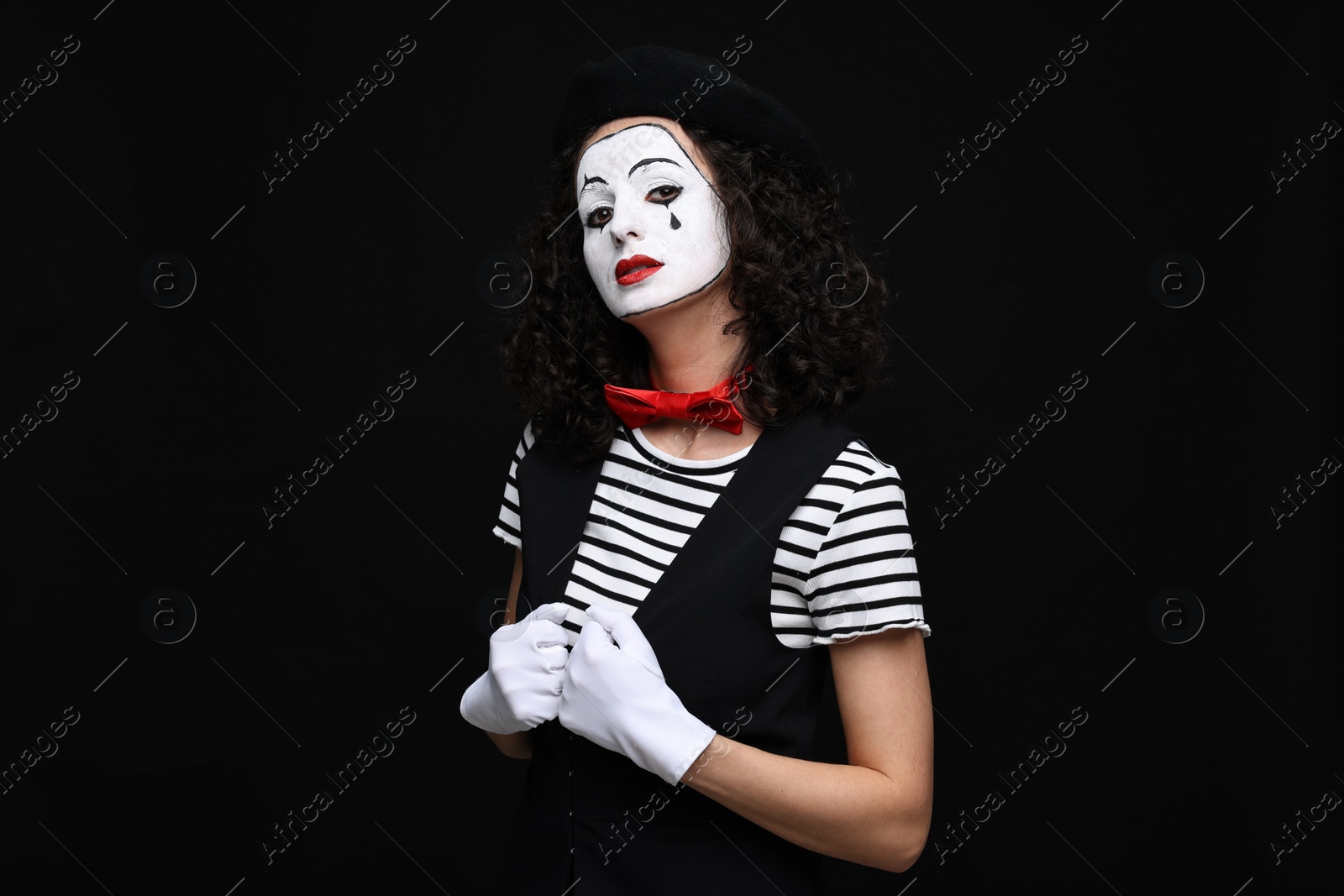 Photo of Young woman in mime costume posing on black background