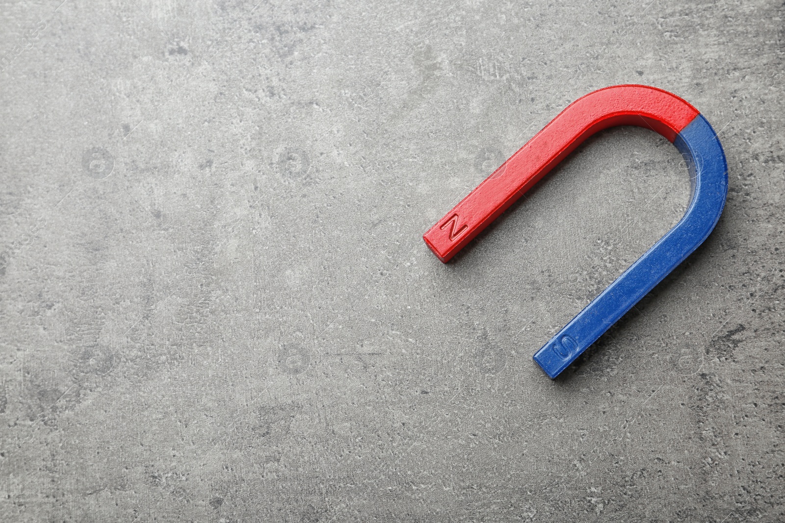 Photo of Red and blue horseshoe magnet on grey background, top view with space for text