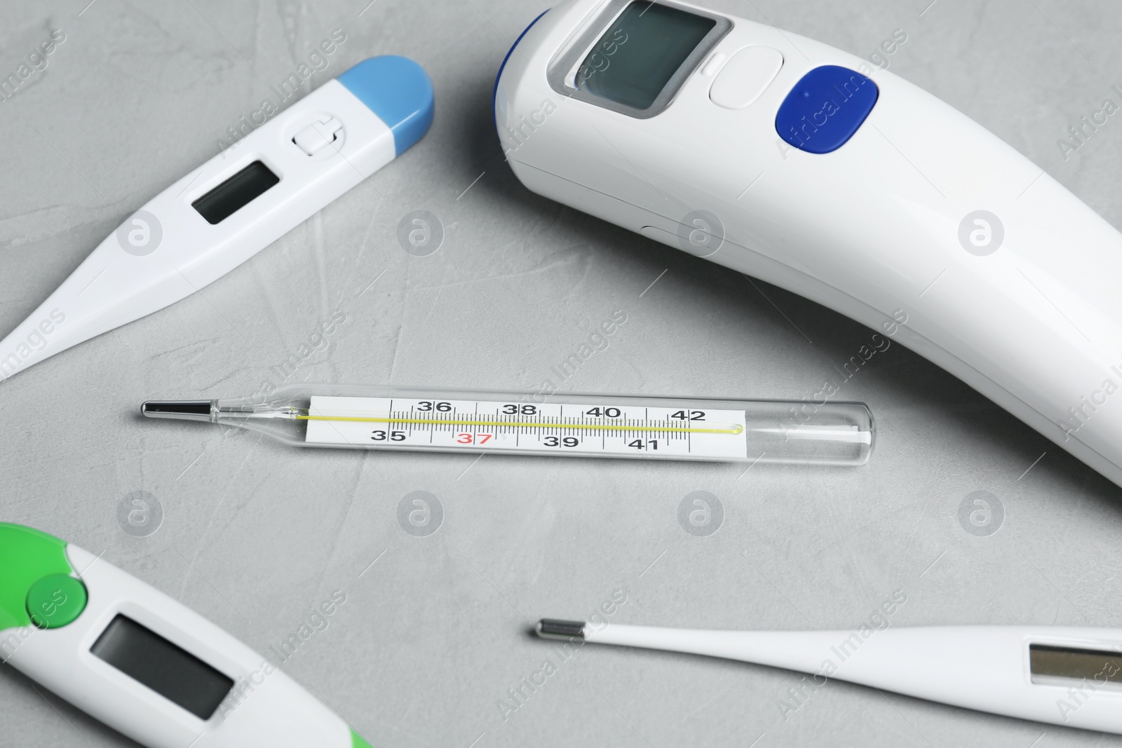 Photo of Mercury, non-contact infrared and digital thermometers on light grey stone background