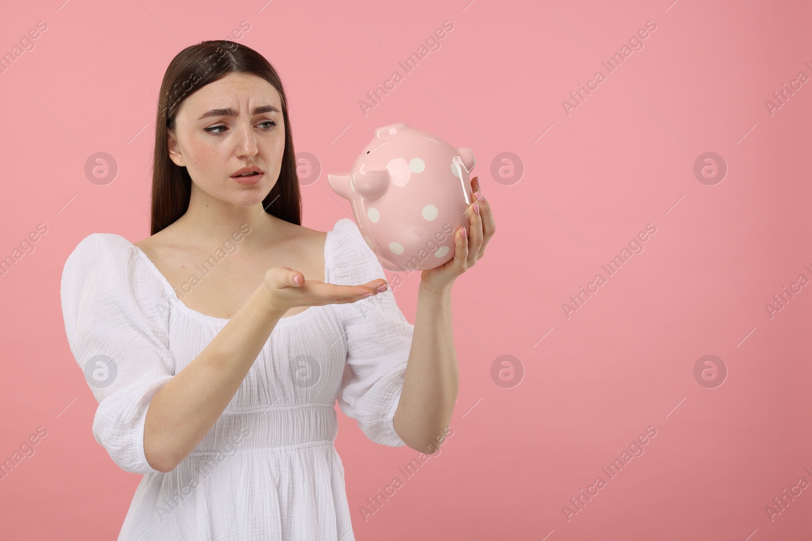 Photo of Sad woman with piggy bank on pink background