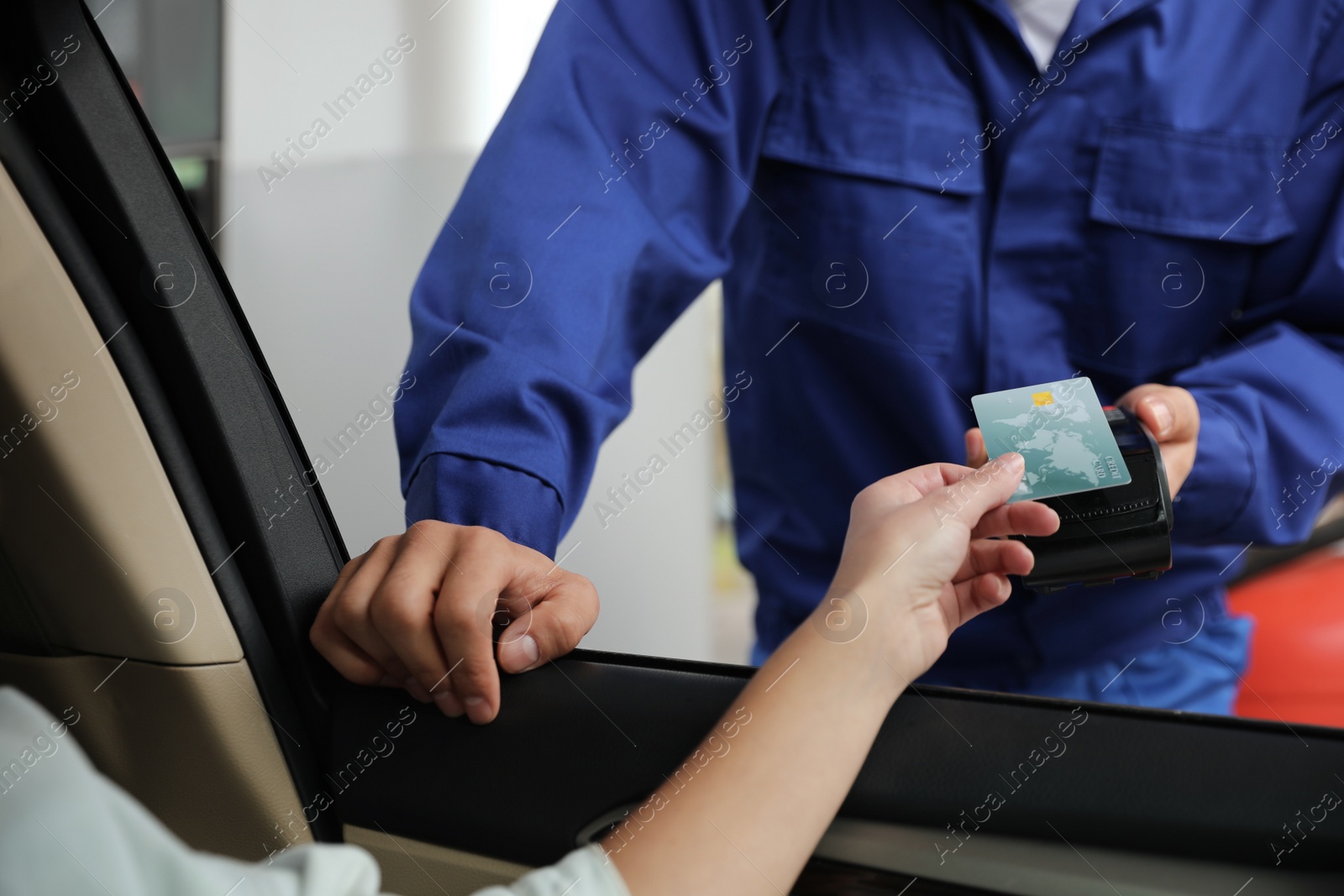 Photo of Woman sitting in car and paying with credit card at gas station, closeup