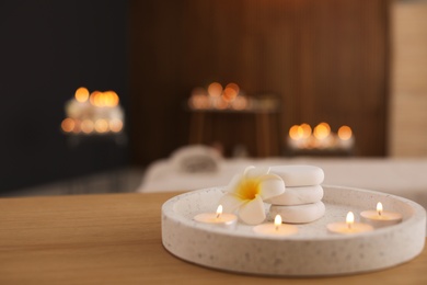 Beautiful composition with burning candles and spa stones on table in salon. Space for text