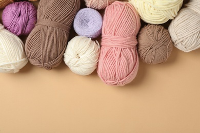 Photo of Soft woolen yarns on beige background, flat lay. Space for text