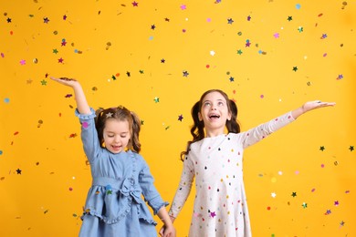 Adorable little children and falling confetti on yellow background