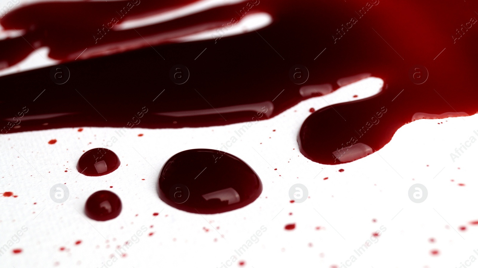 Photo of Stain and drops of blood on light grey background, closeup