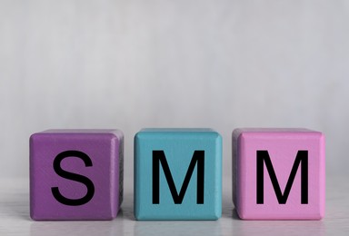 Photo of Colorful cubes with abbreviation SMM (Social media marketing) on grey background