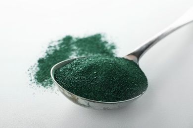 Photo of Spoon with spirulina algae powder on white background