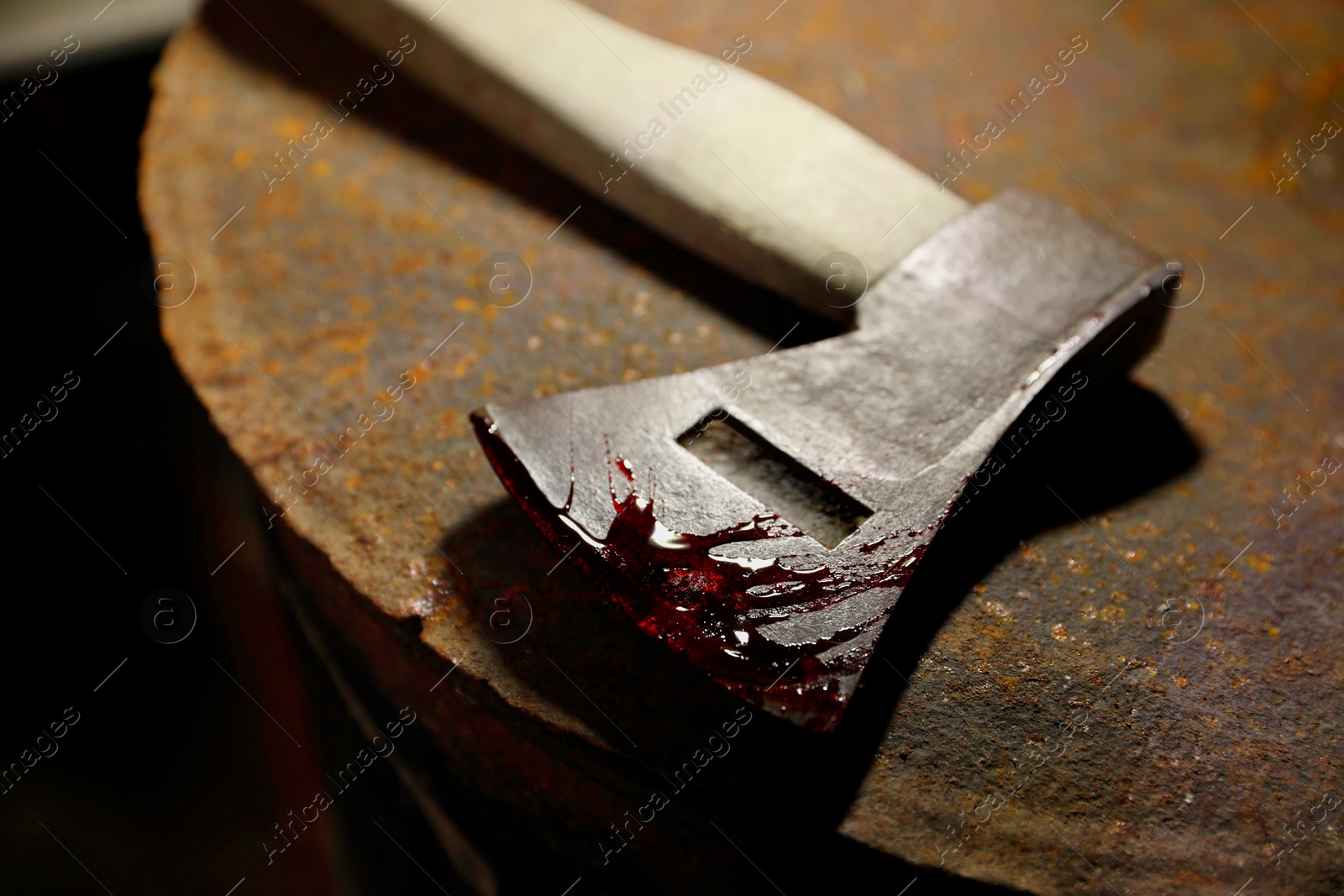 Photo of Axe with blood on rusty metal surface, closeup