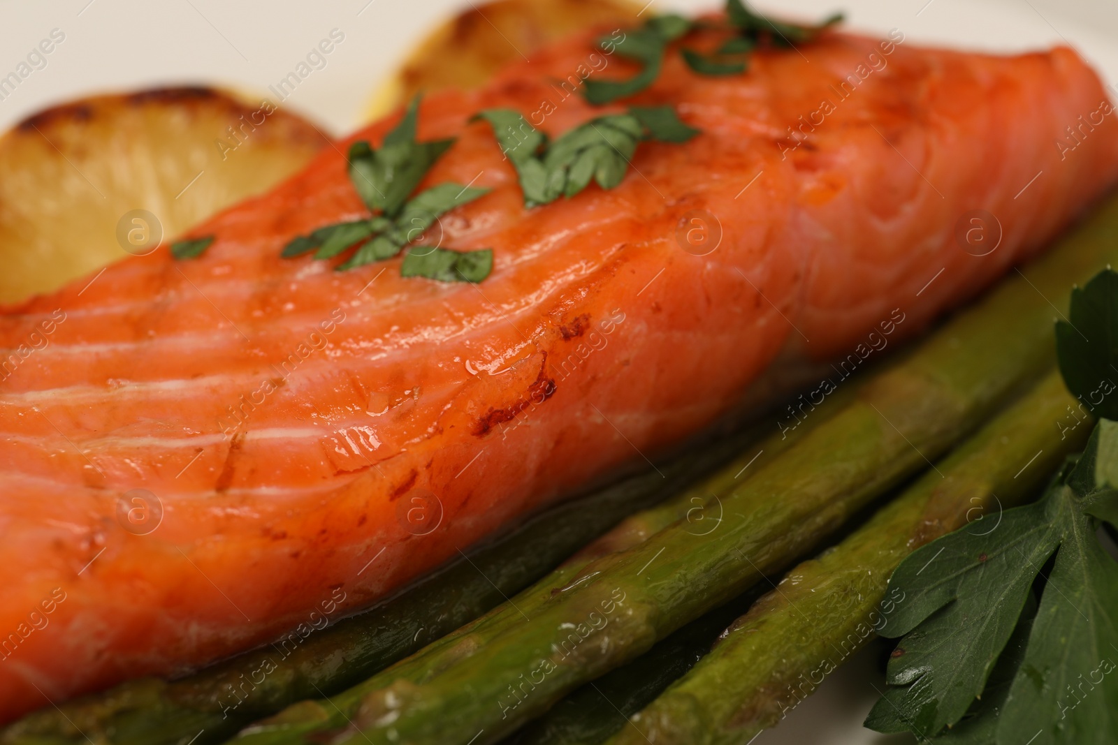 Photo of Tasty grilled salmon with asparagus and parsley, closeup