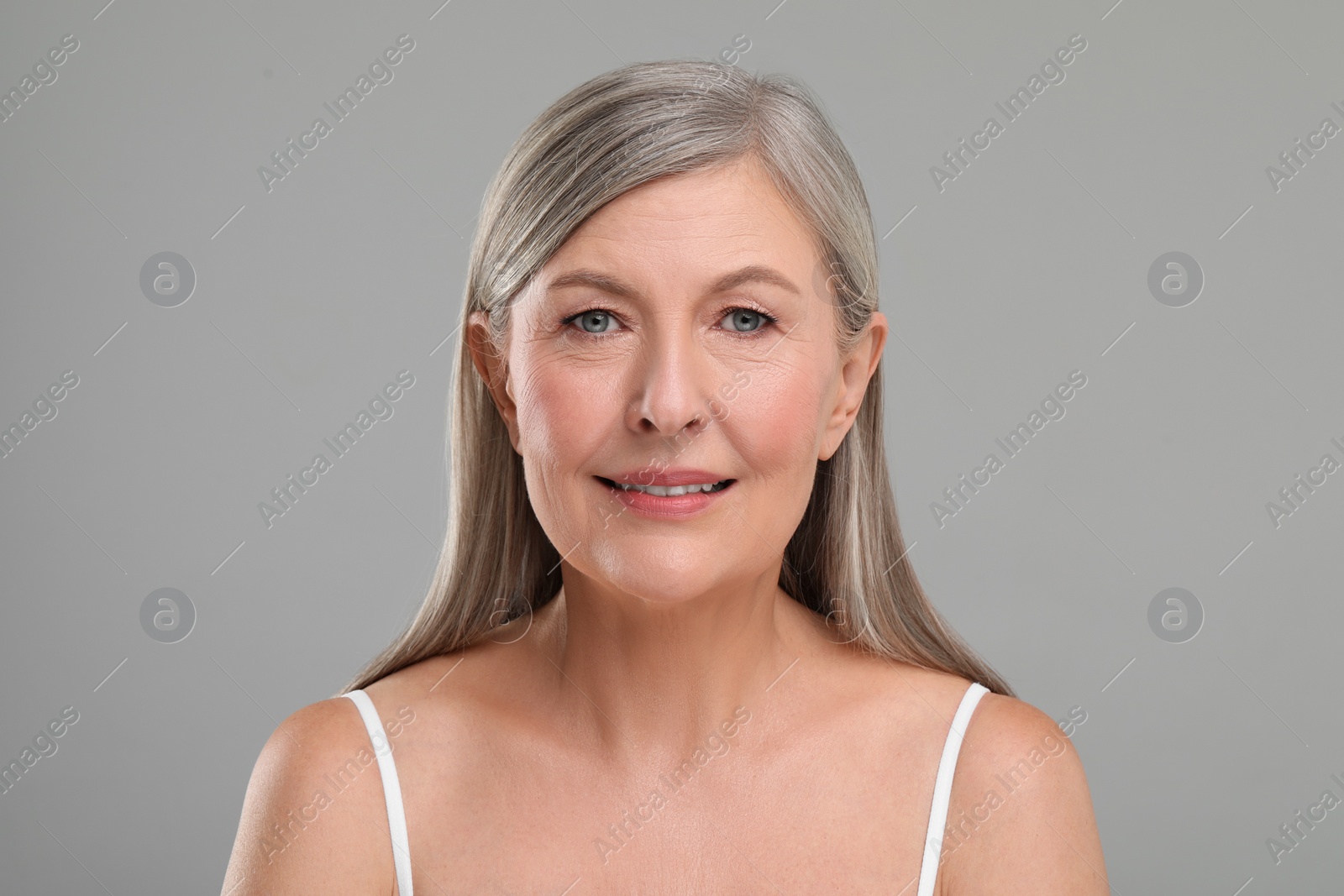 Photo of Beautiful mature woman with healthy skin on gray background