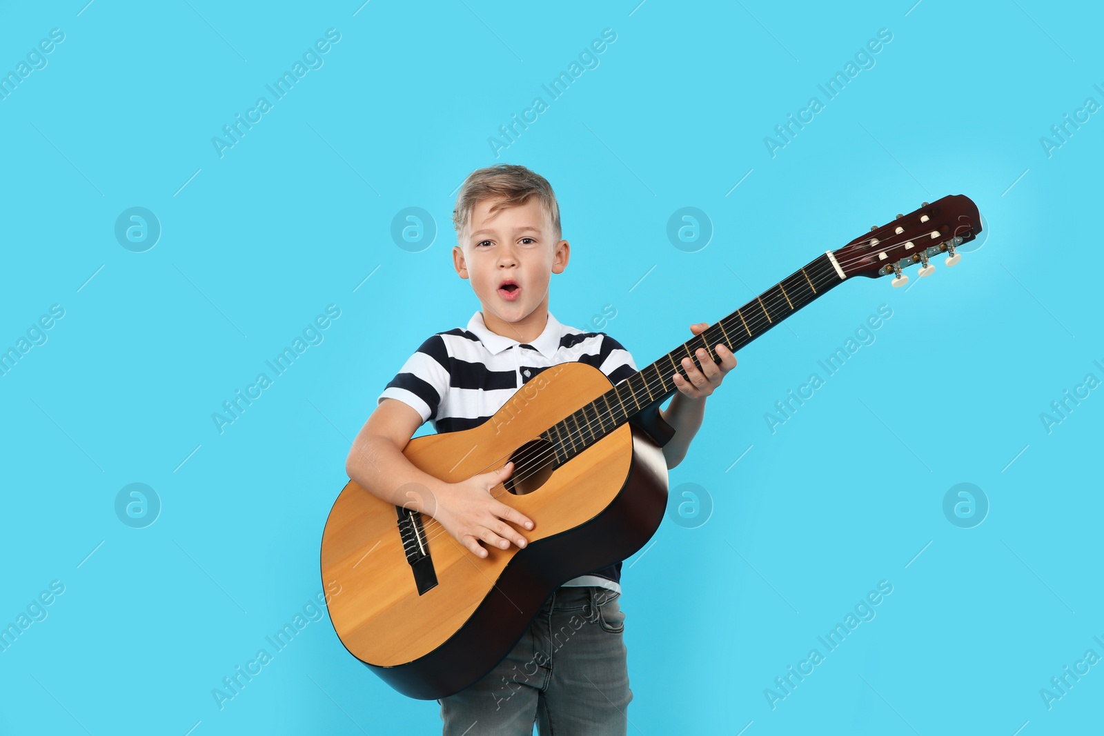 Photo of Portrait of little boy playing guitar on color background