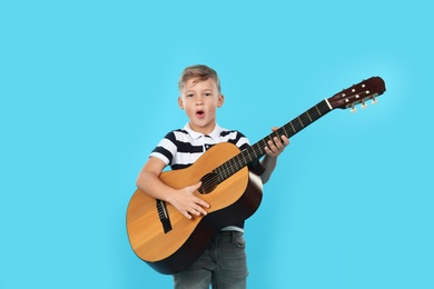 Photo of Portrait of little boy playing guitar on color background