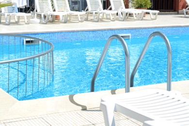 Outdoor swimming pool and loungers at resort sunny day