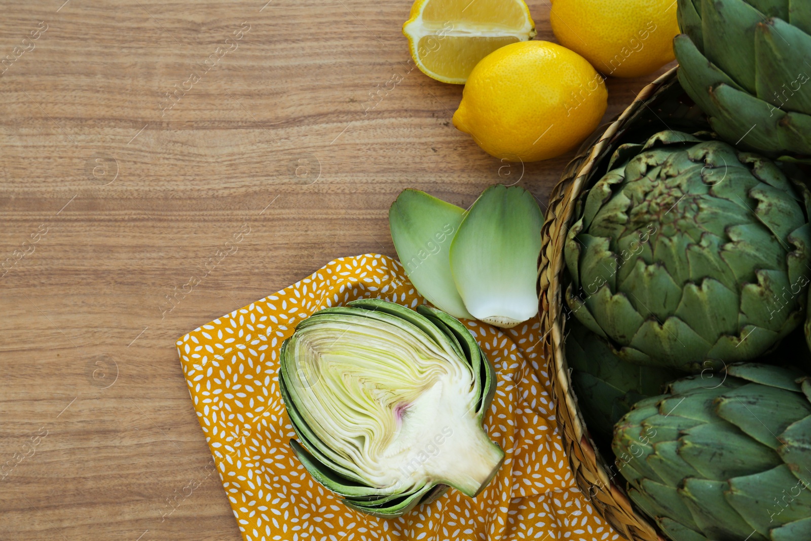 Photo of Artichokes and lemons on wooden table, flat lay