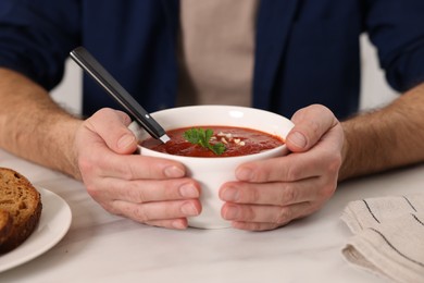 Photo of Man with delicious tomato soup at light table, closeup