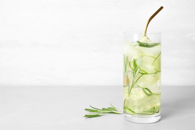 Photo of Glass of refreshing cucumber lemonade on table against light background, space for text. Summer drink