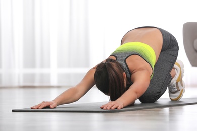 Photo of Young woman in fitness clothes doing exercise at home. Space for text