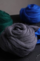 Photo of Colorful felting wool on dark textured table, closeup