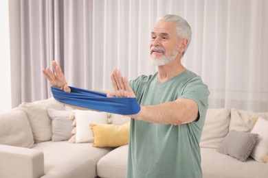 Senior man doing exercise with fitness elastic band at home