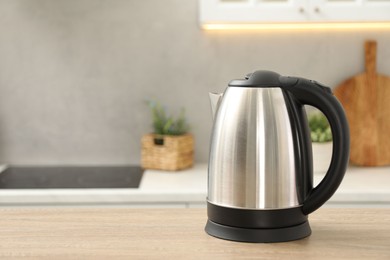 Photo of Modern electric kettle on table in kitchen. Space for text