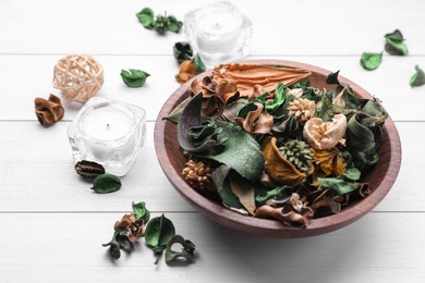 Photo of Aromatic potpourri of dried flowers in bowl on white wooden table