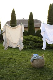 Photo of Clean clothes drying near wicker bag in backyard