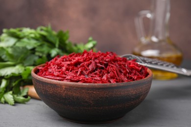 Photo of Grated red beet in bowl on gray table, closeup