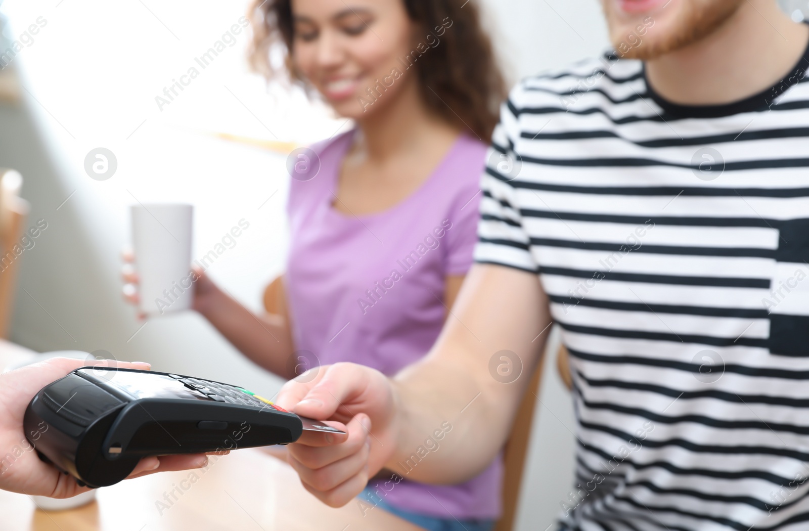 Photo of Clients using credit card machine for non cash payment in cafe, closeup